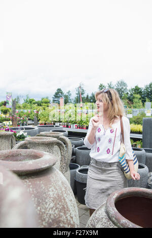 Donna matura la scelta di urn in serra, Augsburg, Baviera, Germania Foto Stock