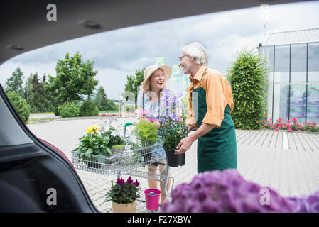 Shop assistant aiutando un cliente a mettere le piante in un baule auto, Augsburg, Baviera, Germania Foto Stock