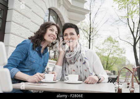 Due amici del cafè sul marciapiede e telefonare, Baviera, Germania Foto Stock