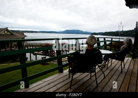 Giovane seduti sulla veranda che si affaccia su un passaggio di rilevamento aprile Point Resort Isola Quadra BC Canada Foto Stock