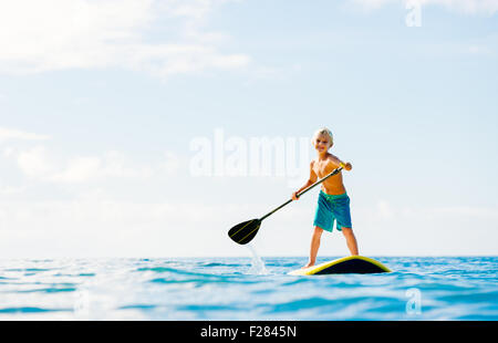 Ragazzo giovane avendo divertimento Stand Up Paddling nell'oceano Foto Stock