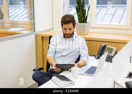 Imprenditore casual con tavoletta digitale alla scrivania Foto Stock