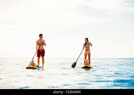 Famiglia avente Fun Stand Up Paddling insieme nell'oceano sulla splendida mattina di sole Foto Stock