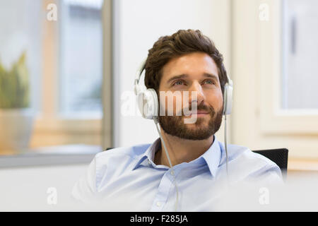 Malinconici imprenditore ascolto di musica con cuffie Foto Stock