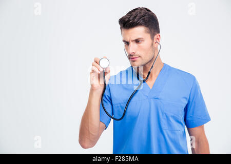 Ritratto di un medico di sesso maschile tenendo uno stetoscopio isolato su uno sfondo bianco Foto Stock