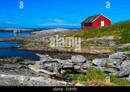 Red Timber house presso la costa rocciosa del Mare di Norvegia vicino a BUD, Kommune Fraena, Romsdal penisola, Norvegia Foto Stock