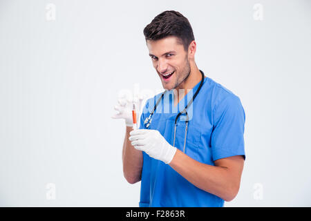 Ritratto di un divertente medico maschio tenendo la siringa isolato su uno sfondo bianco Foto Stock