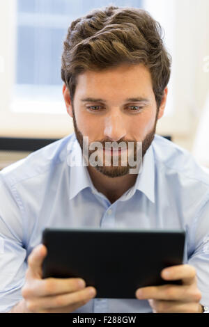 Business Casual Uomo al lavoro su tablet PC in ufficio Foto Stock