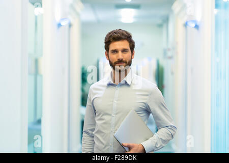 Ritratto di bello barbuto business man in corridoio ufficio. guardando la fotocamera Foto Stock