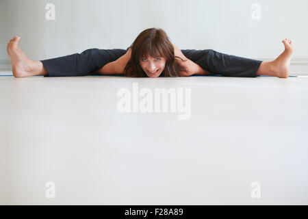 Donna sorridente facendo yoga. Ampio angolo seduti piegare in avanti pone. Praticanti femmina Upavistha Konasana esercizio in palestra. Foto Stock