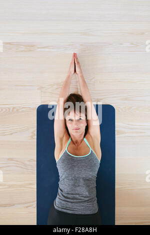 Vista superiore della donna sdraiata sul pavimento facendo esercizio di stretching. Donna Fitness esercita sul materassino yoga. Foto Stock