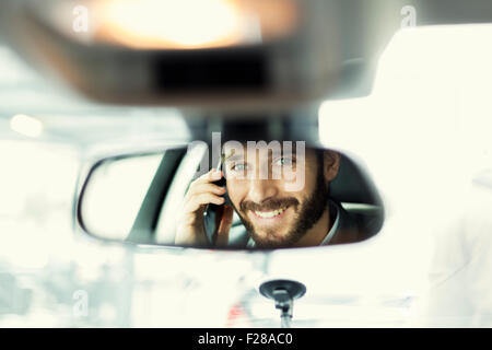 Allegro uomo sul telefono cellulare in auto. La riflessione nello specchio Foto Stock