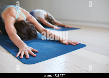 Due donne facendo stretching allenamento sul tappetino fitness. Le femmine di eseguire lo yoga sul tappeto di esercizio in palestra. Bambino pongono, Balasana. Foto Stock