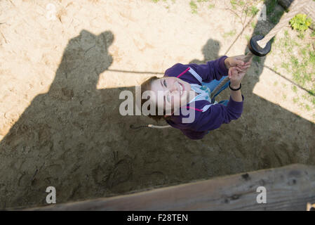 Ragazza salendo sulla corda nel parco giochi, Monaco di Baviera, Germania Foto Stock