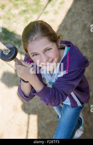 Ragazza salendo sulla corda nel parco giochi, Monaco di Baviera, Germania Foto Stock