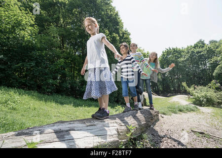 Le ragazze in equilibrio su tronco di albero nel parco giochi, Monaco di Baviera, Germania Foto Stock