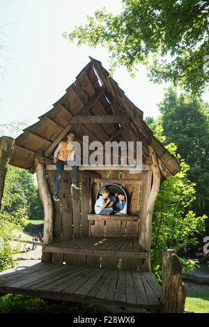 Due ragazzi e una ragazza su un cottage nel parco giochi avventura, Monaco di Baviera, Germania Foto Stock
