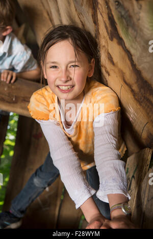 Ragazza arrampicata su albero di casa in un parco giochi, Monaco di Baviera, Germania Foto Stock