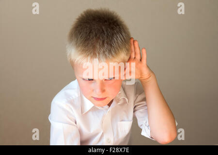 Bambino overhearing ascolto qualcosa con la mano al concetto dell'orecchio Foto Stock