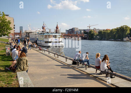 Persone relax presso il fiume Sprea vicino Oberbaumbrücke, dell'ex muro di Berlino la striscia della morte, Berlino, Germania Foto Stock