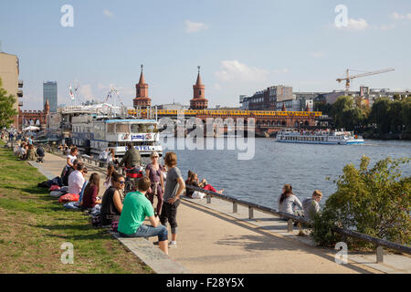Persone relax presso il fiume Sprea vicino Oberbaumbrücke, dell'ex muro di Berlino la striscia della morte, Berlino, Germania Foto Stock