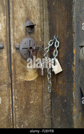 Bloccato con due lucchetti porta di un abbandonato fatiscente casa antica. Foto Stock