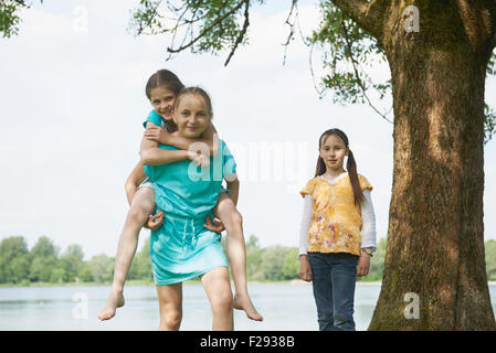 Ragazza dando piggyback ride al suo amico femmina, Baviera, Germania Foto Stock