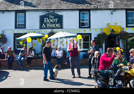 I clienti a decorate village pub, Greystoke Cumbria in attesa nella luce del sole per l arrivo del tour della Gran Bretagna cycle race 2015 FASE 5 Foto Stock