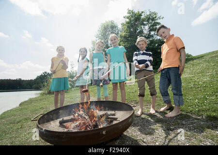 Gruppo di amici preparare le salsicce sul fuoco, Baviera, Germania Foto Stock