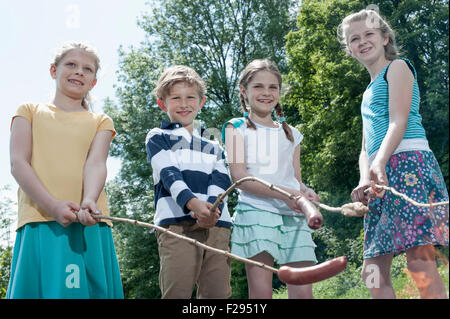 Gruppo di amici preparare le salsicce sul fuoco, Baviera, Germania Foto Stock