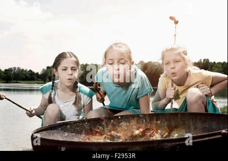 Tre amici preparare le salsicce sul fuoco, Baviera, Germania Foto Stock