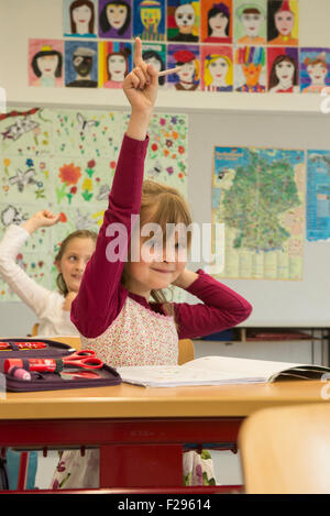 Scolaresche con mani alzate in classe, Monaco, Baviera, Germania Foto Stock