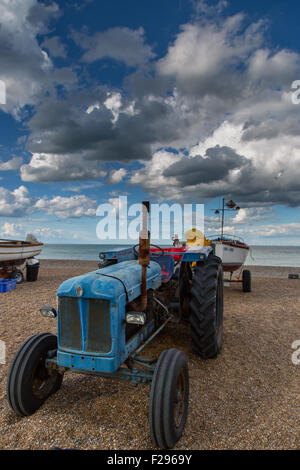 Drammatica cielo sopra Cley spiaggia a nord di Norfolk, fisher (trattori Fordson Power Major) e barche Foto Stock