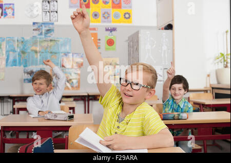 Scolaresche con mani alzate in classe, Monaco, Baviera, Germania Foto Stock