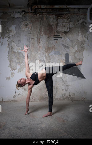 Metà donna adulta la pratica della mezza luna in studio di yoga, Monaco di Baviera, Germania Foto Stock