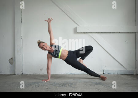 Metà donna adulta lato praticanti plank pongono in studio di yoga, Monaco di Baviera, Germania Foto Stock