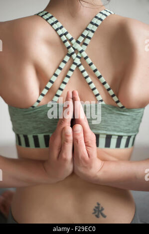 Vista posteriore di una metà donna adulta pratica pashchima namaskarasana posizione nello studio di yoga, Monaco di Baviera, Germania Foto Stock