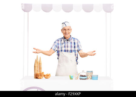 Studio shot di una matura gelato venditore di stare dietro a una fase di stallo e la realizzazione di un gesto accogliente isolati su sfondo bianco Foto Stock