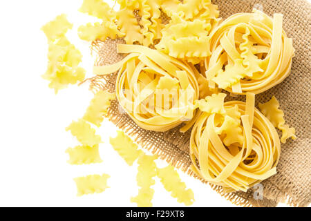 La pasta italiana La cucina a base di noodle nidificano sul pezzo di sacco su sfondo bianco Foto Stock