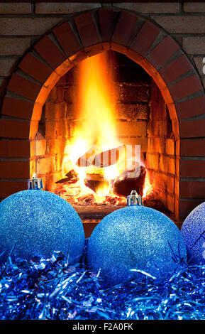 Blu palle di Natale e tinsel con aprire il fuoco nel camino home Foto Stock