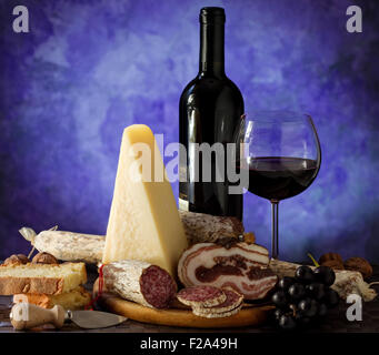 Salumi parmigiano e un bicchiere di vino rosso su sfondo viola Foto Stock