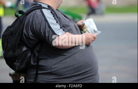 Un uomo sovrappeso mangia il cibo spazzatura Foto Stock