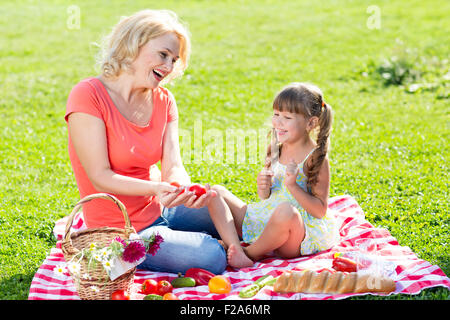 Famiglia mamma e bambino picnic sul prato con verdure Foto Stock