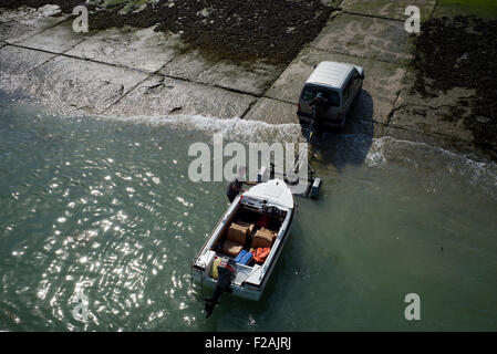 Due uomini caricamento piccola barca sul rimorchio, Le Treport, Normandia, Francia Foto Stock