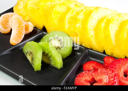 Frutta a fette su nero piattino Foto Stock