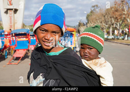 Giovane ragazza malgascia che porta il bambino sulla schiena in città Antsirabe, Vakinankaratra, Madagascar, Africa Sud-est Foto Stock