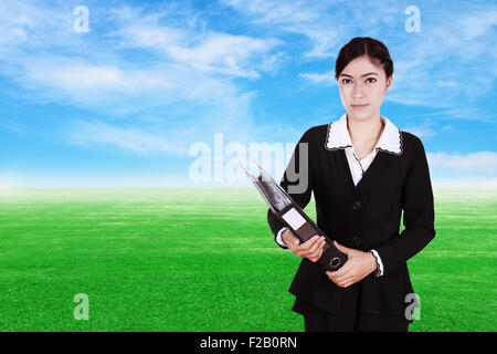 Business donna apposita cartella documenti con erba verde campo e cielo blu sullo sfondo Foto Stock