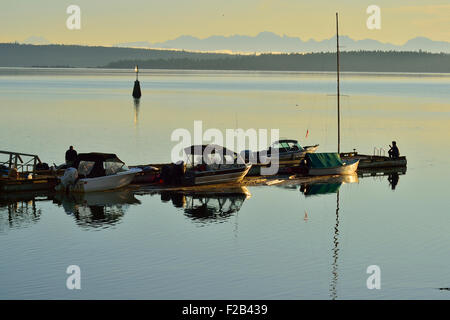 Una immagine di un molo sullo Stretto di Georgia vicino Ladysmith sull'Isola di Vancouver con barche ormeggiate e persone a sunrise. Foto Stock