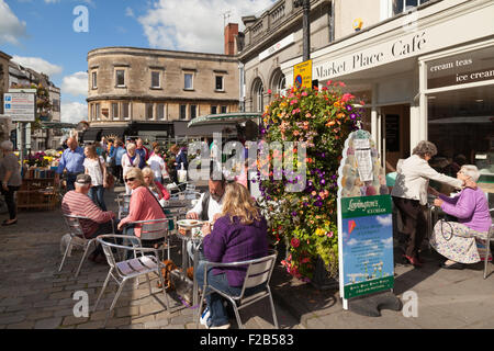 La gente seduta in un caffè con tavoli all'aperto in una giornata di sole, Pozzi city centre, Somerset England Regno Unito Foto Stock