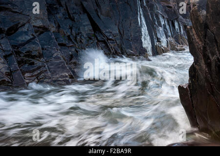 Rottura d'onda tra le rocce in Caer bwdy bay in Pembrokeshire, West Wales. Foto Stock